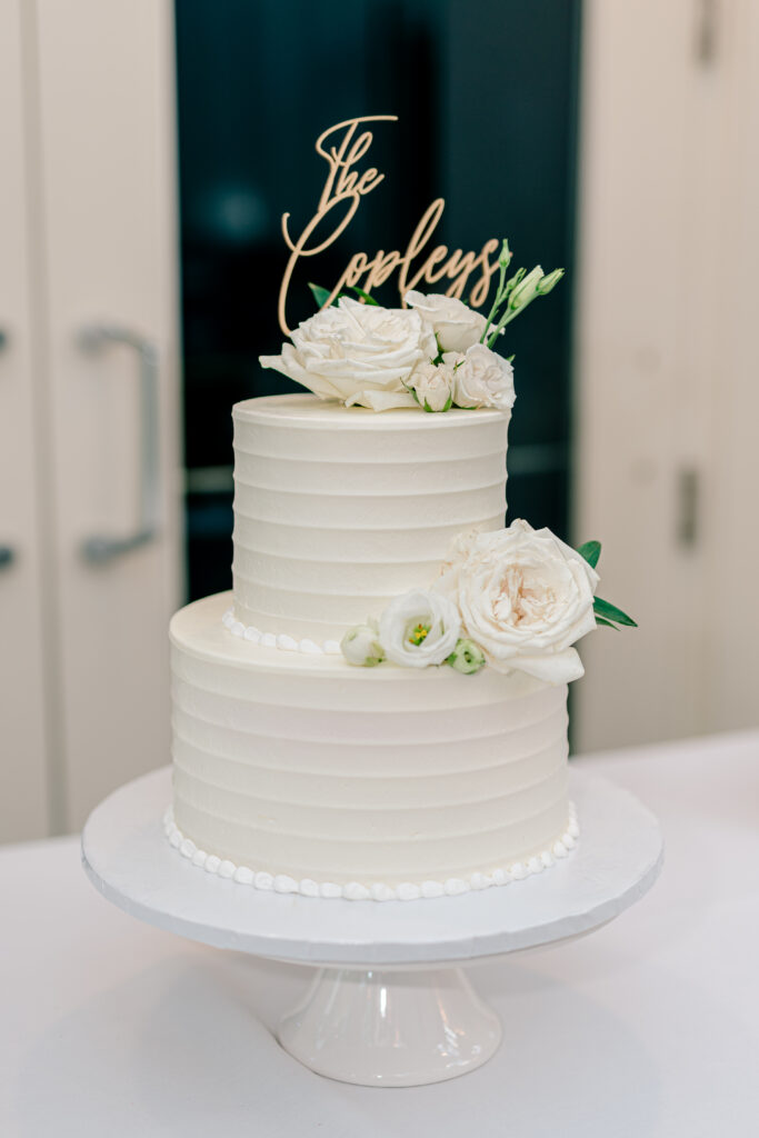 A simple white buttercream wedding cake with white flowers during a tented wedding reception at Historic Blenheim in Fairfax, Virginia