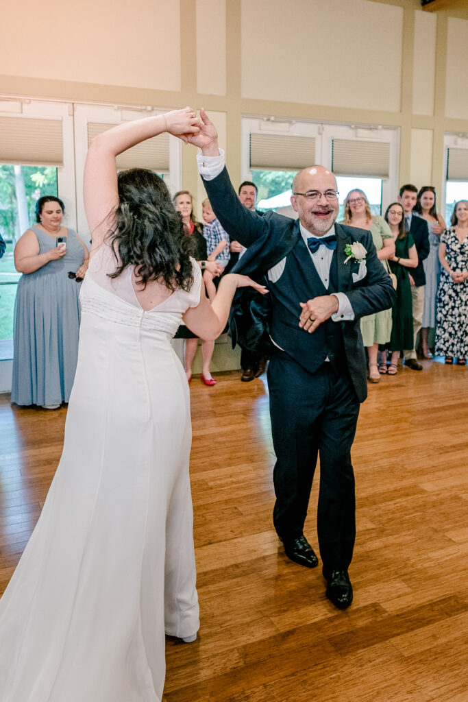 A father smiles at the camera as he twirls the bride during a tented wedding reception at Historic Blenheim in Fairfax, Virginia