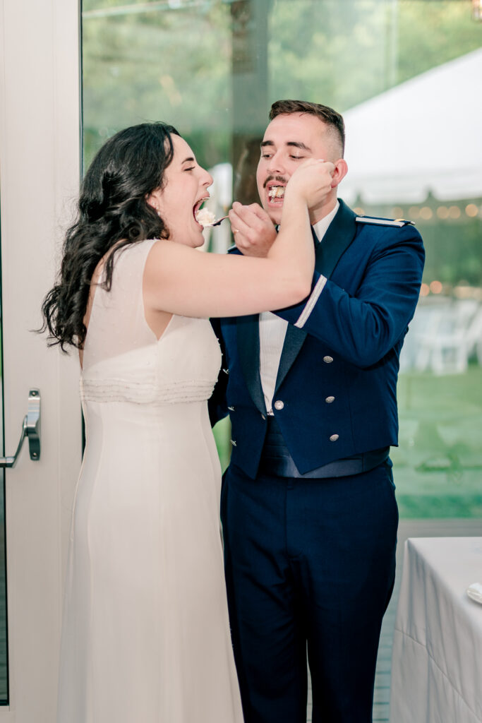 A bride and groom feeding each other cake during a tented wedding reception at Historic Blenheim in Fairfax, Virginia