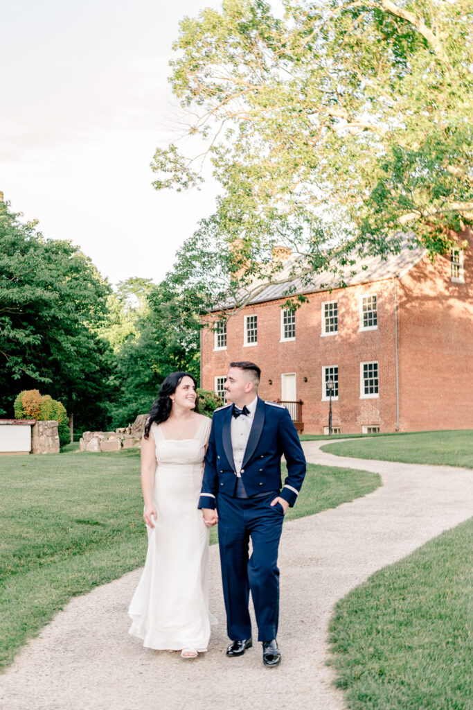 A bride and groom walking together at golden hour during a tented wedding reception at Historic Blenheim in Fairfax, Virginia