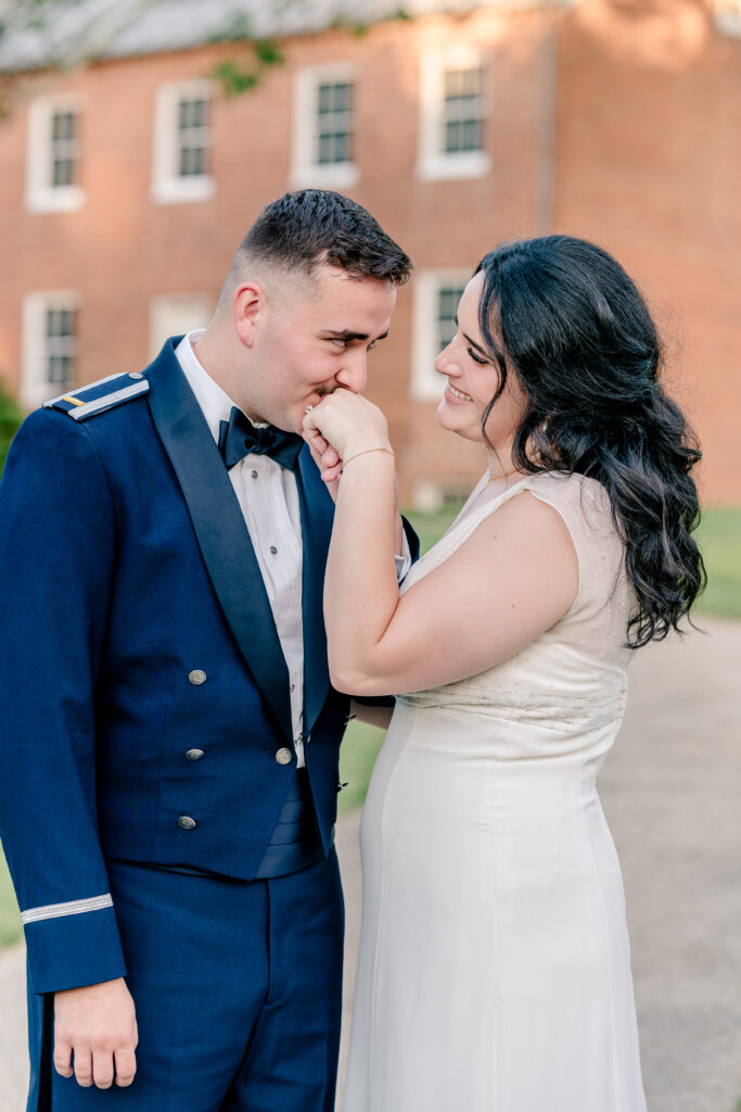 A groom kissing the hand of his bride during a tented wedding reception at Historic Blenheim in Fairfax, Virginia