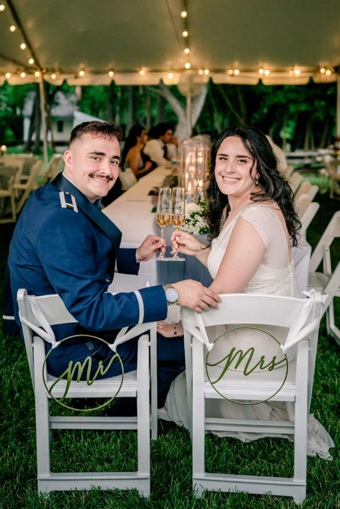 A bride and groom toast with their personalized champagne glasses during a tented wedding reception at Historic Blenheim in Fairfax, Virginia