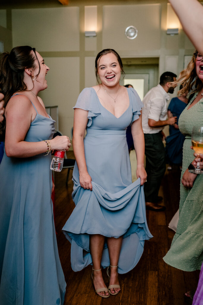 A bridesmaid holds her dress above her feet during a tented wedding reception at Historic Blenheim in Fairfax, Virginia