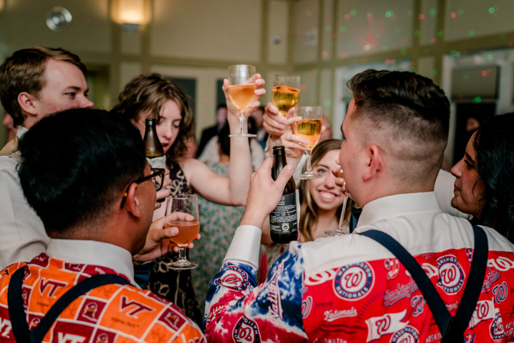 A group of guests toasting their glasses on the dance floor during a tented wedding reception at Historic Blenheim in Fairfax, Virginia