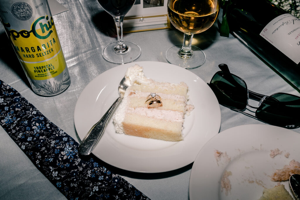 A late night flat lay with the wedding rings inside a slice of cake during a tented wedding reception at Historic Blenheim in Fairfax, Virginia