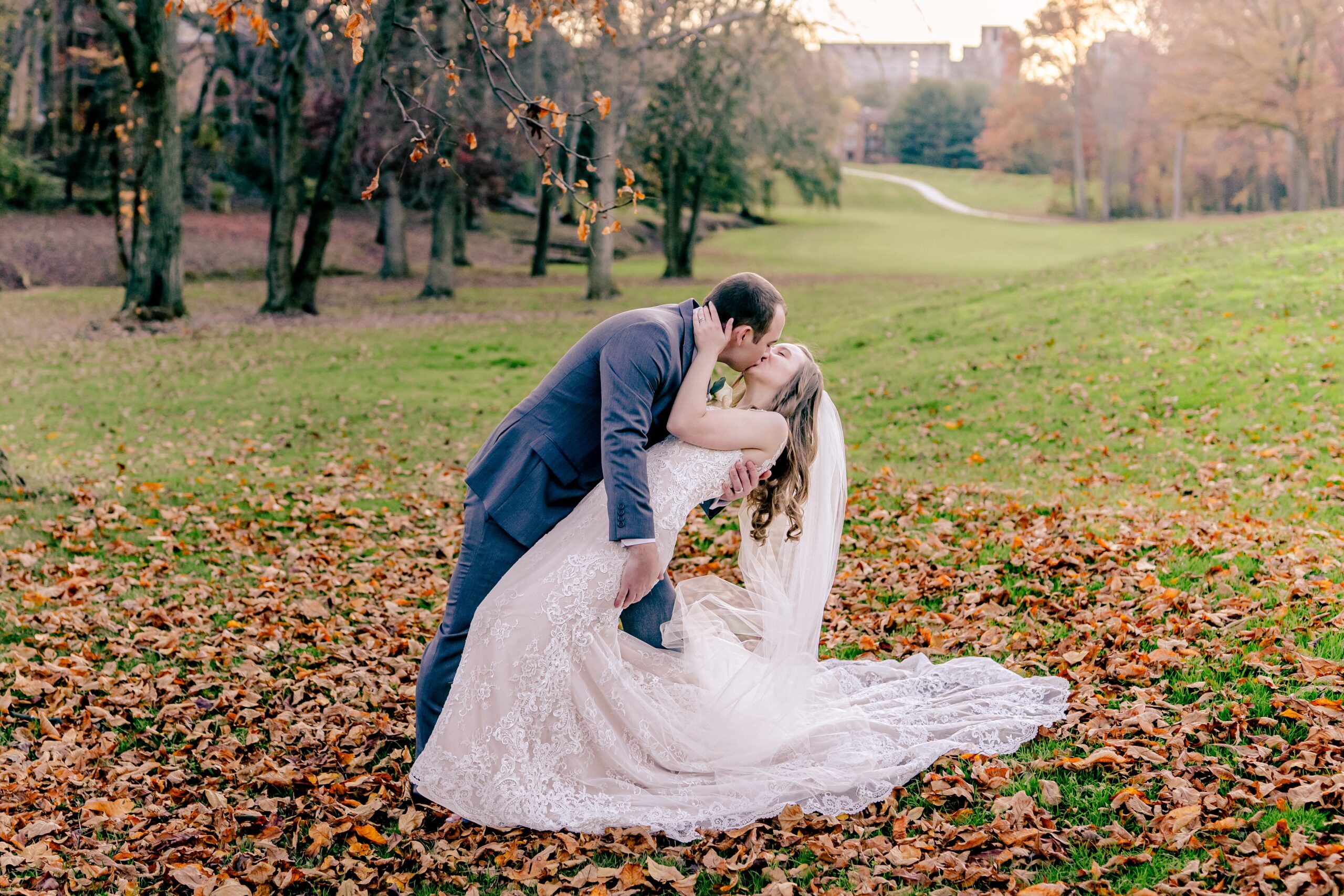 A bride and groom share a romantic kiss surrounded by fall foliage during their Hidden Creek Country Club wedding in Fairfax Virginia