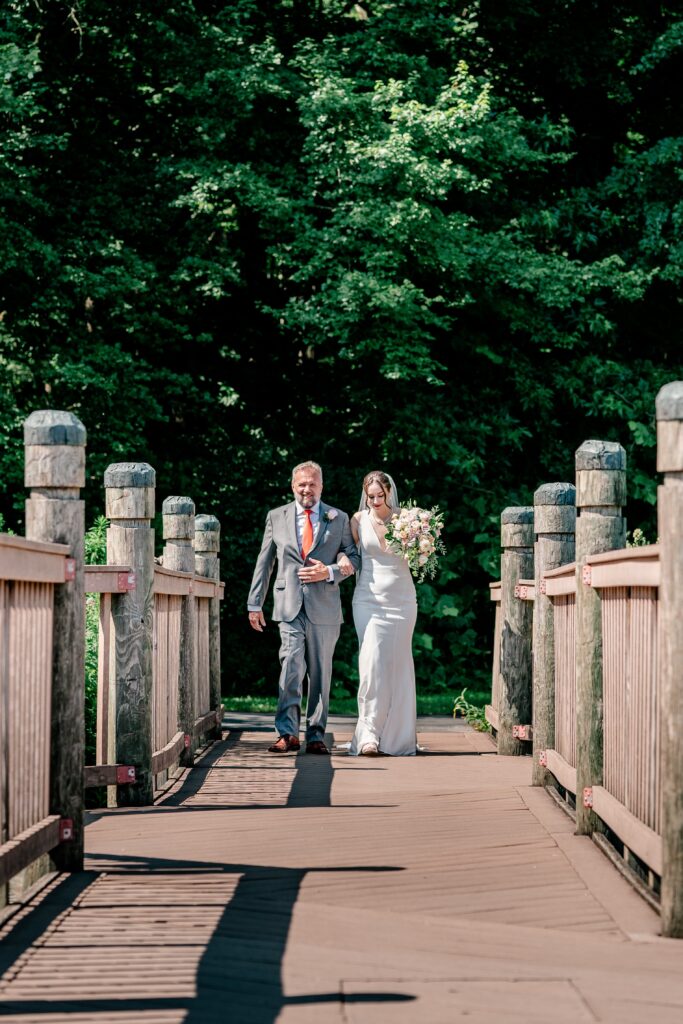 A bride and her father walk down the aisle for a micro wedding at Meadowlark Botanical Gardens in Vienna, Virginia