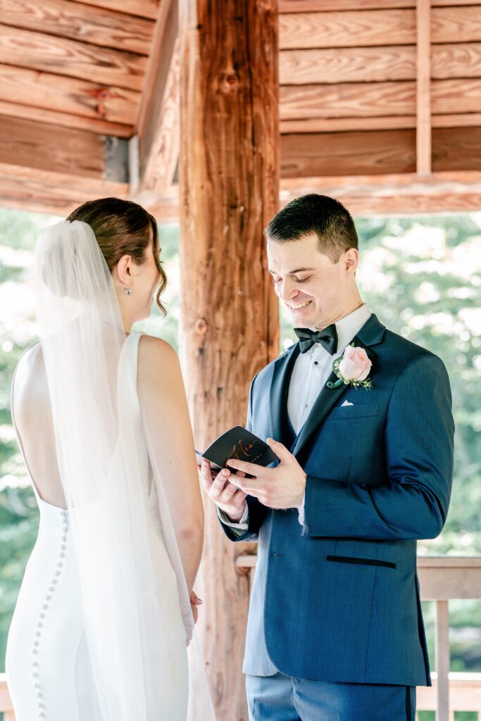 A groom smiling down at his vow book