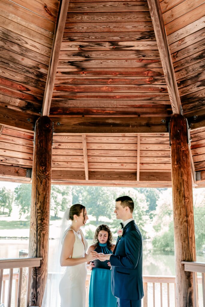 A bride and groom exchanging rings under a gazebo