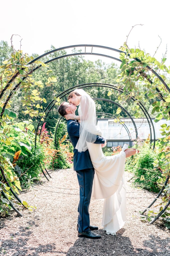 A bride and groom share a kiss inside a garden