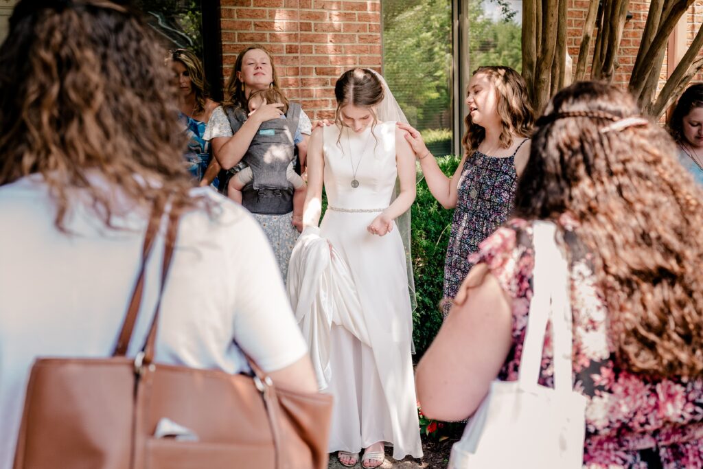 A bride prays with her friends before her Sheraton Reston wedding