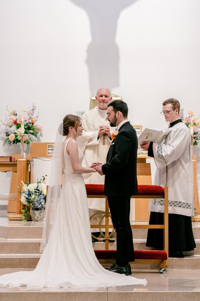 A bride and groom exchanging vows during their wedding at St. Joseph Catholic Church in Herndon, Virginia