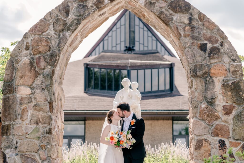 A bride and groom share a kiss in front of the church after their wedding at St. Joseph Catholic Church in Herndon, Virginia