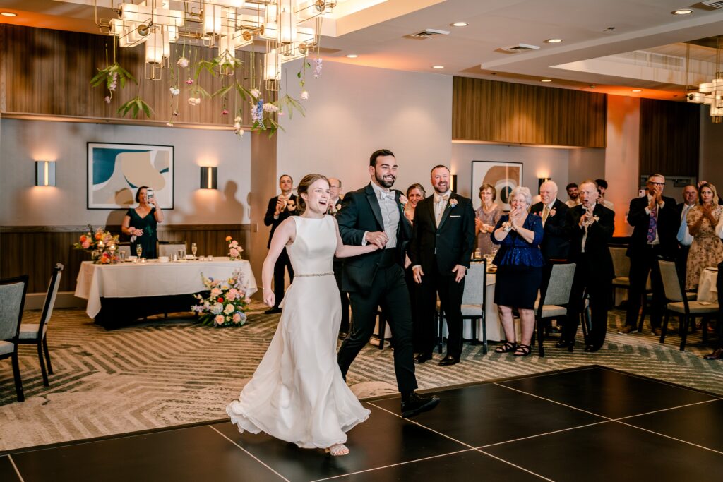 An excited bride and groom making their grand entrance for a Sheraton Reston wedding reception