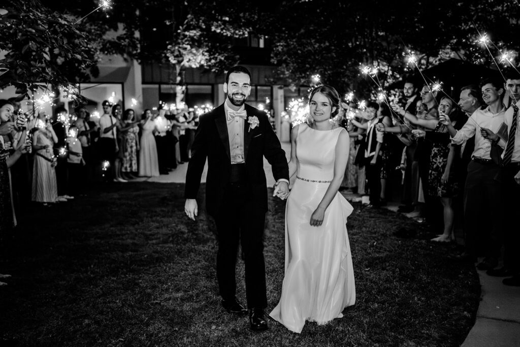 A bride and groom smile during their sparkler exit after a Sheraton Reston wedding reception