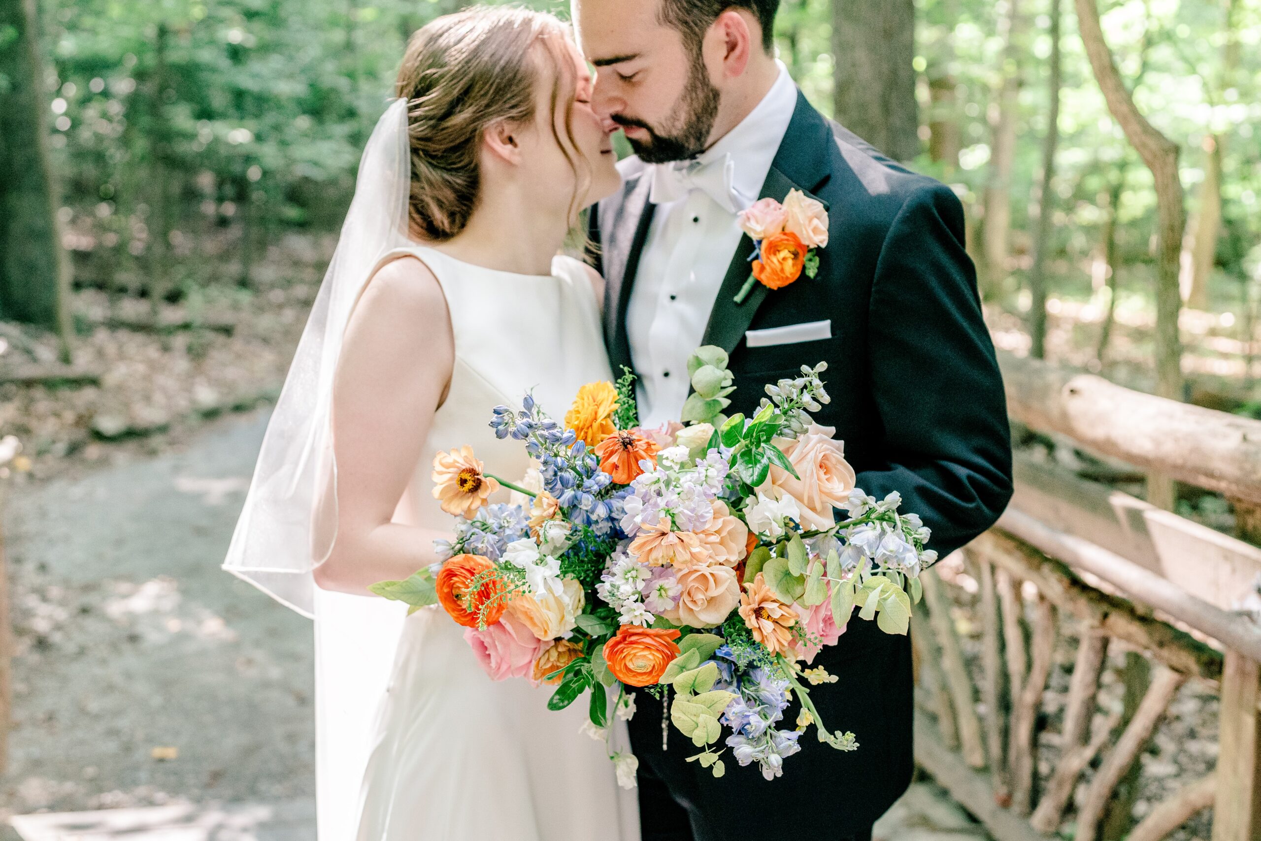 A bride and groom leaning in for a kiss while holding colorful flowers for a Sheraton Reston wedding reception