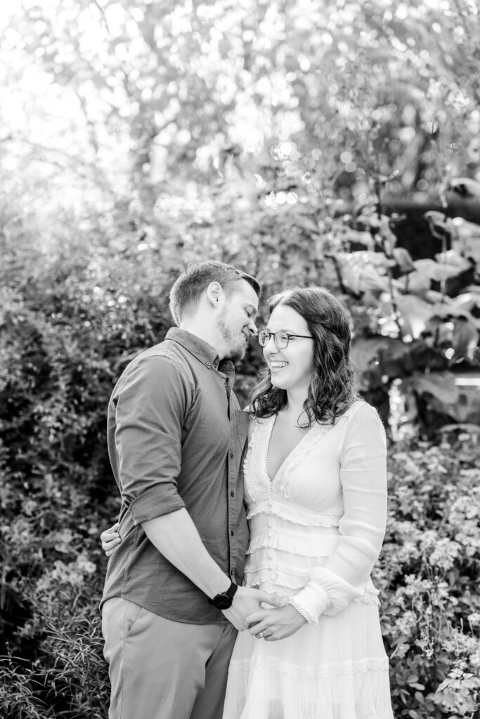 A black and white image of an engaged couple laughing