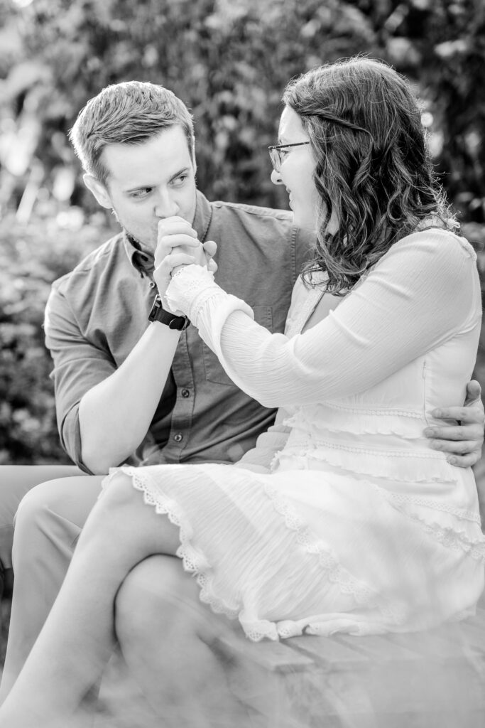 A man kissing his fiancée’s hand during their Brookside Gardens engagement session in Silver Spring, MD