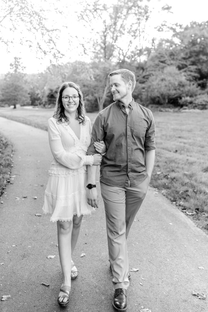 A black and white image of an engaged couple walking together along a path by Washington DC wedding photographer Beauty of the Soul Studio