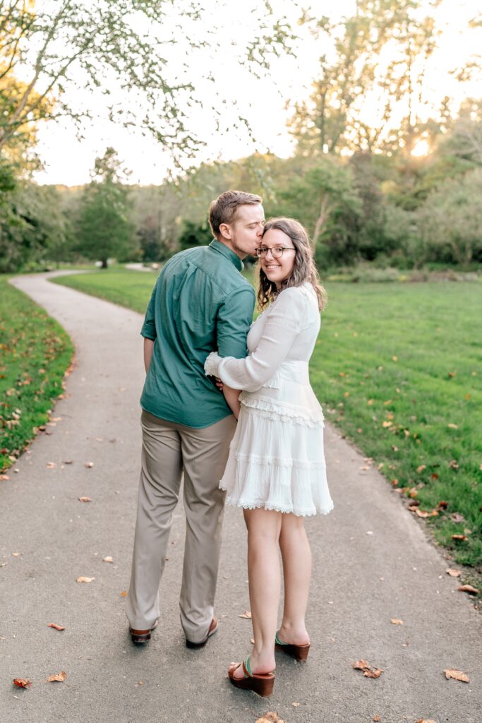 A couple walking together as she looks back at the camera during their Brookside Gardens engagement session in Silver Spring, MD