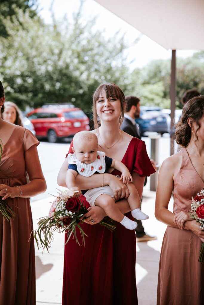 A bridesmaid holding a baby for a wedding in Fredericksburg Virginia