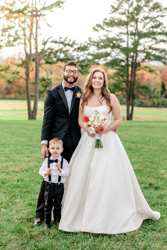 A bride and groom posing with a boy during a wedding at The Barn at Edgewood