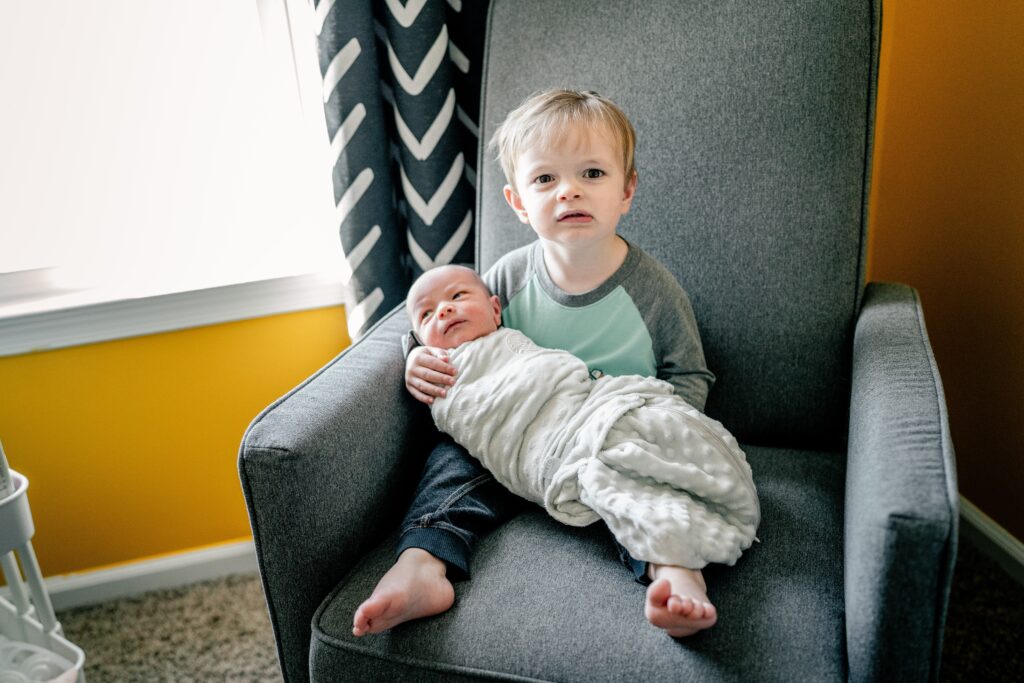 A toddler holding his new baby brother