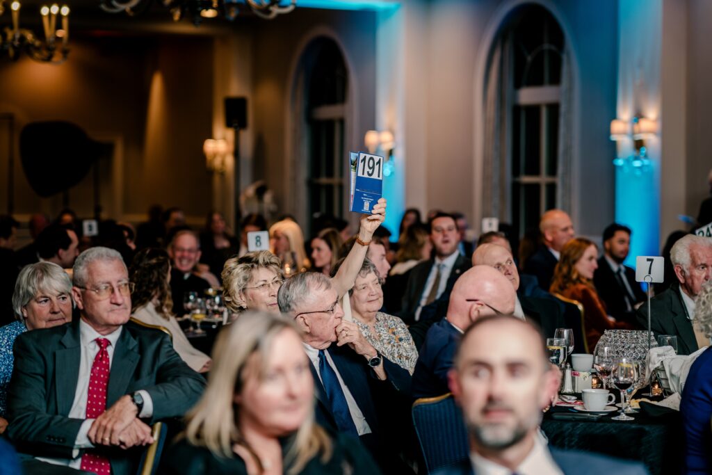 Guests raising paddles during a dinner auction for Divine Mercy Care