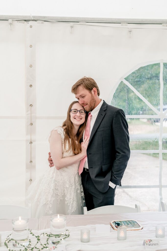 A bride and groom snuggling up during their tented wedding reception