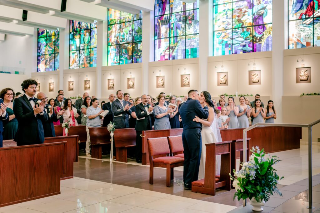 The bride and groom's first kiss during a wedding at St. Philip Catholic Church in Fairfax, Virginia