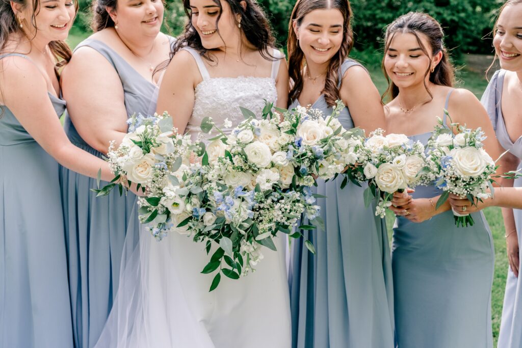 A bridal party smiling at one another showing off their bouquets after a wedding at St. Philip Catholic Church in Fairfax, Virginia