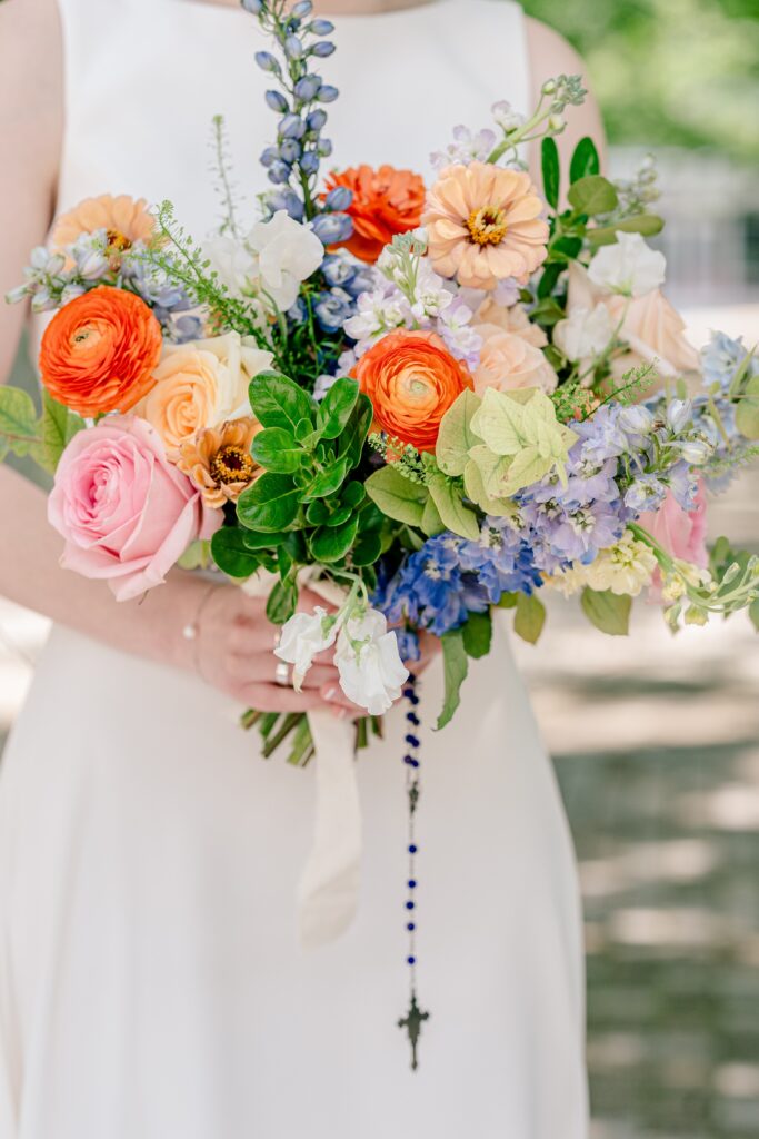 A bridal bouquet with a rosary hanging from it during a Catholic wedding in Northern Virginia