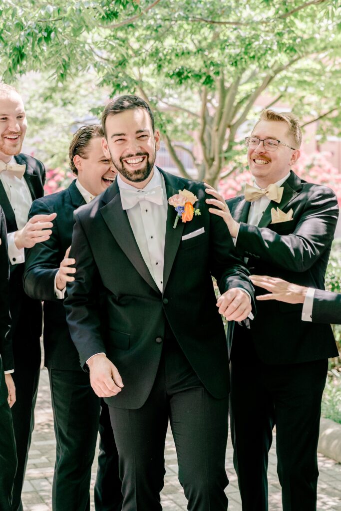 A groom and his groomsmen laughing together during a Catholic wedding in Northern Virginia