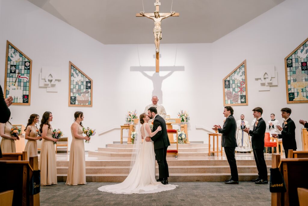 A bride and groom share their big kiss during a Catholic wedding in Northern Virginia