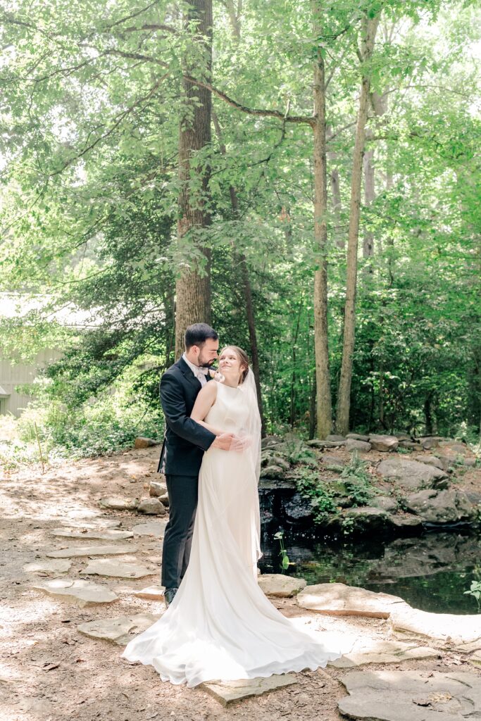 A bride and groom pose for a classic portrait looking at one another in a garden background