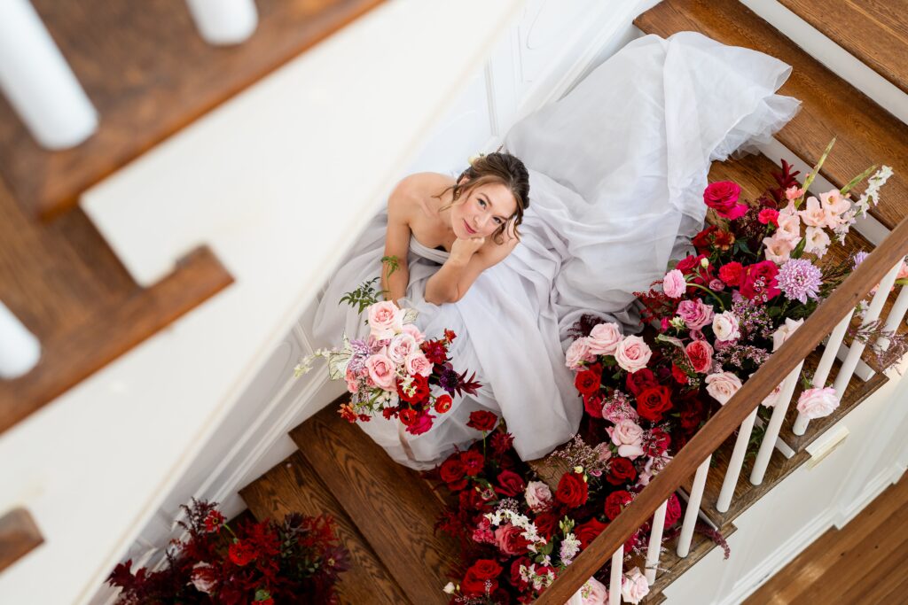 A bride sitting on the staircase surrounded by florals for a wedding at Rust Manor House in Leesburg Virginia