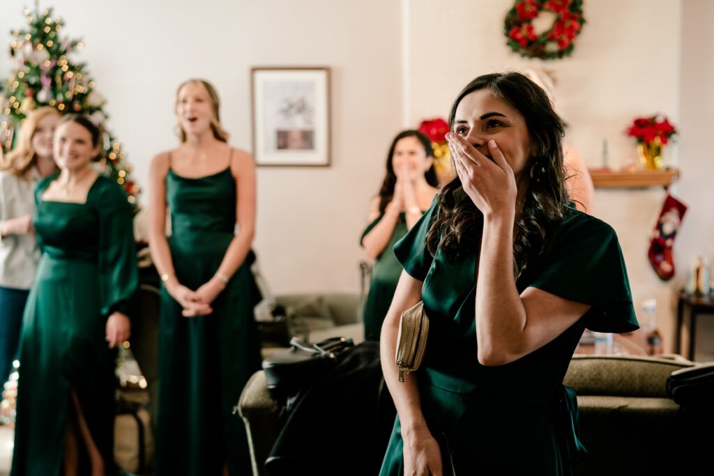 Bridesmaids look surprised as they see the bride for the first time during her Christmas themed wedding