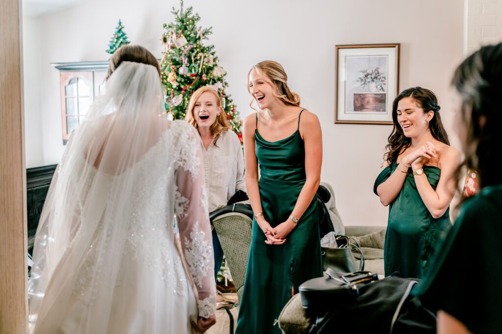 Bridesmaids laugh as they see the bride during a first look before her Catholic wedding in Northern Virginia