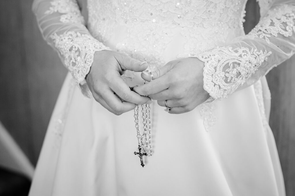 A close up of a bride's hands holding a rosary before her Catholic wedding