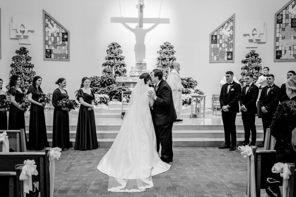 A father kisses his daughter on the cheek during her Catholic wedding