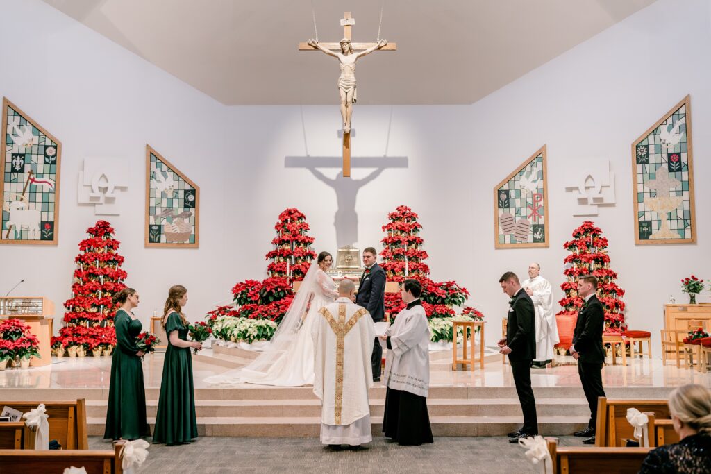 A bride and groom standing with their wedding party beside them during a Christmas themed wedding at St. Joseph Catholic Church in Herndon Virginia