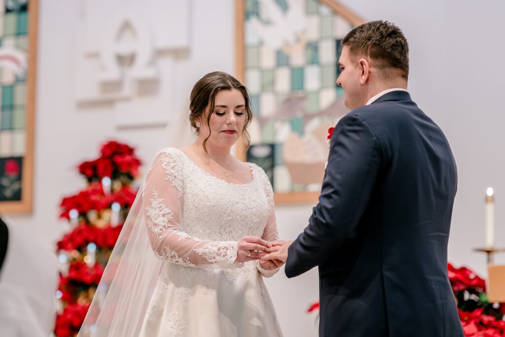 A bride placing the ring on her groom's finger during their wedding