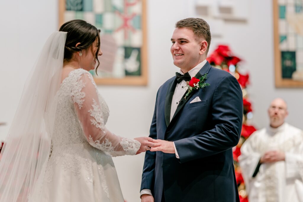 A groom smiling at his bride during their ring exchange