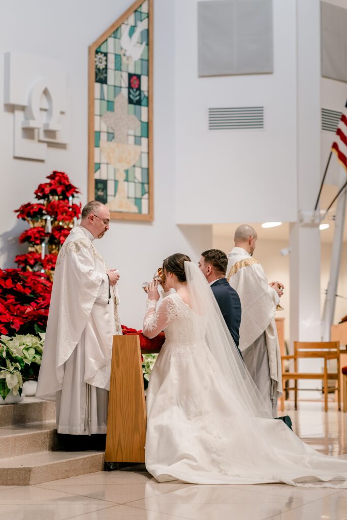 A bride receiving Communion during a Christmas themed wedding at St. Joseph Catholic Church in Herndon Virginia