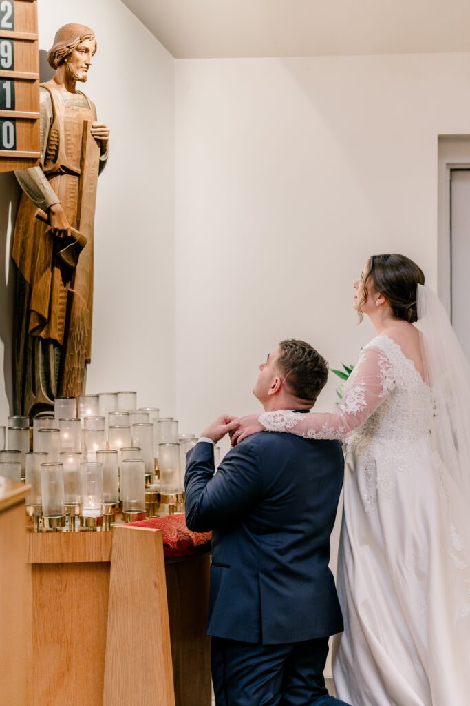 A bride and groom presenting lilies to St. Joseph during their Catholic wedding