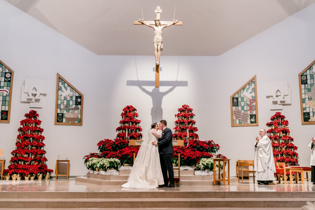 A bride and groom share a kiss during their Christmas themed wedding at St. Joseph Catholic Church in Herndon Virginia