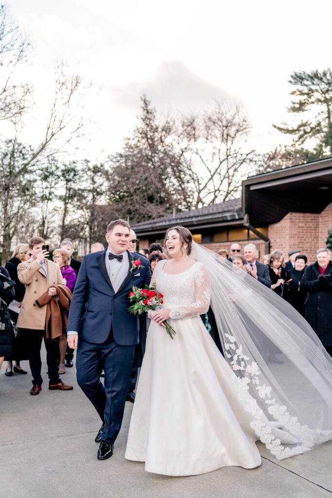 A bride and groom smile as they're surrounded by family