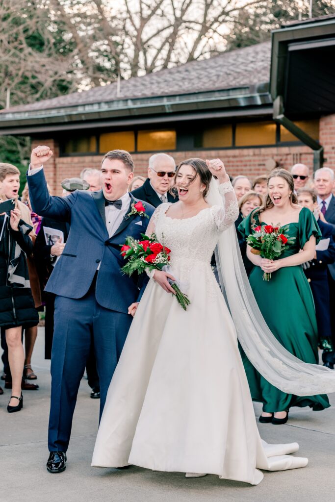 A bride and groom cheering a performer at their wedding