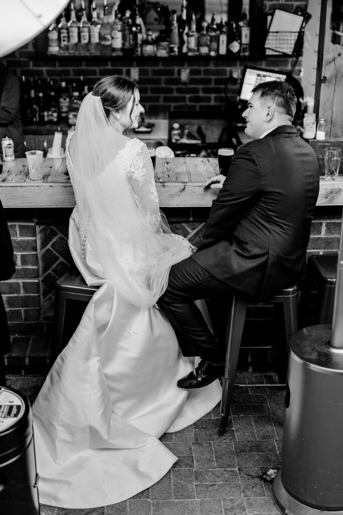 A bride and groom sit at the bar together