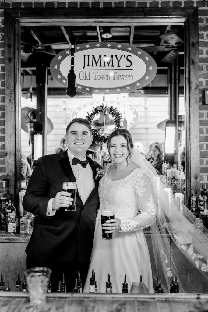 A bride and groom pose for a photo behind the bar at Jimmy's Old Town Tavern in Herndon Virginia